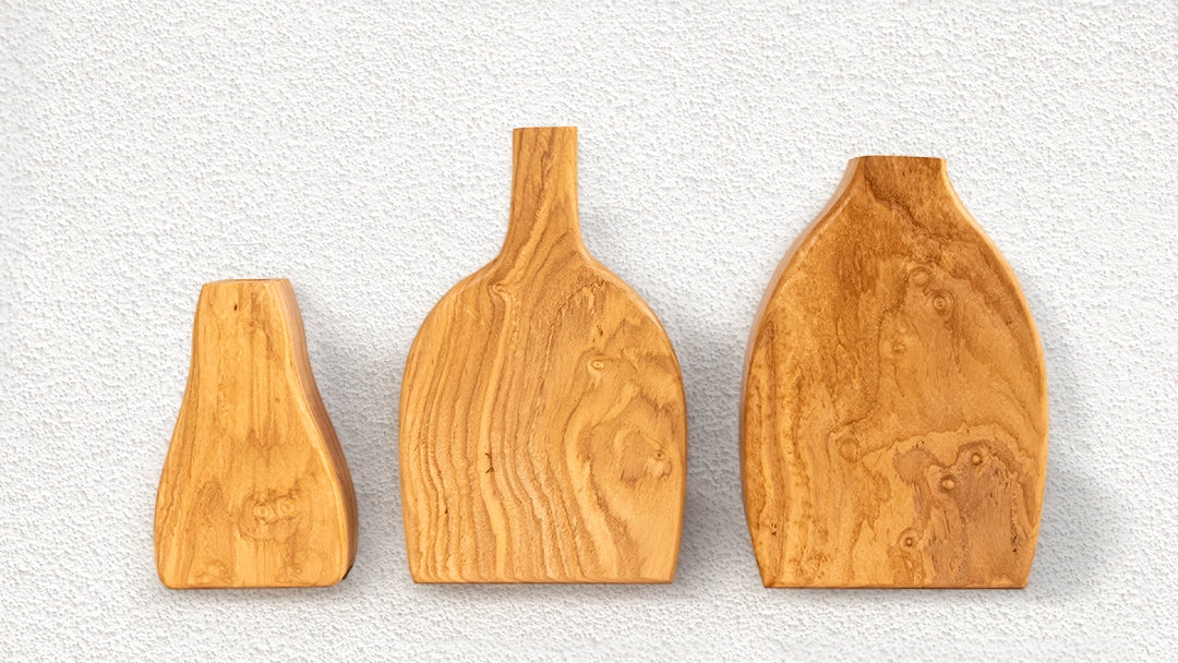 Three handcrafted olive wood decorative blocks of different shapes and sizes, displayed against a textured white background.